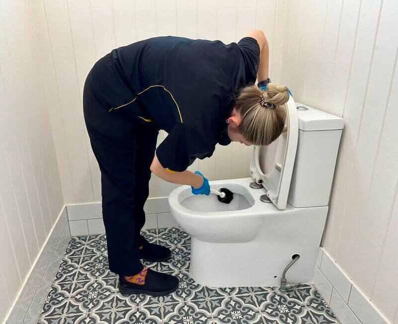 Fully trained professional house cleaner Kate-lyn scrubbing the toilet with a toilet brush
