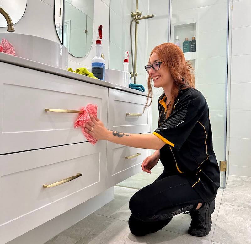 Maid2Match cleaning professional Mariachiara smiling while cleaning bathroom drawers