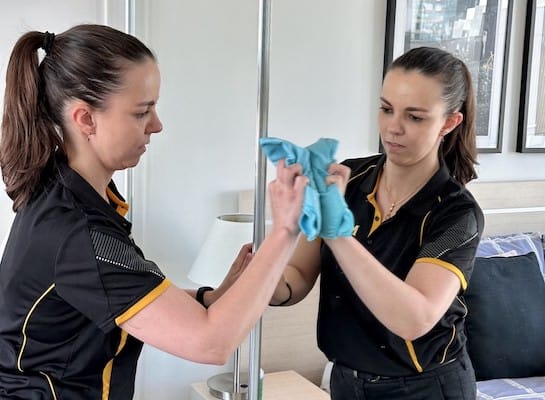 Larissa cleaning a bedroom mirror