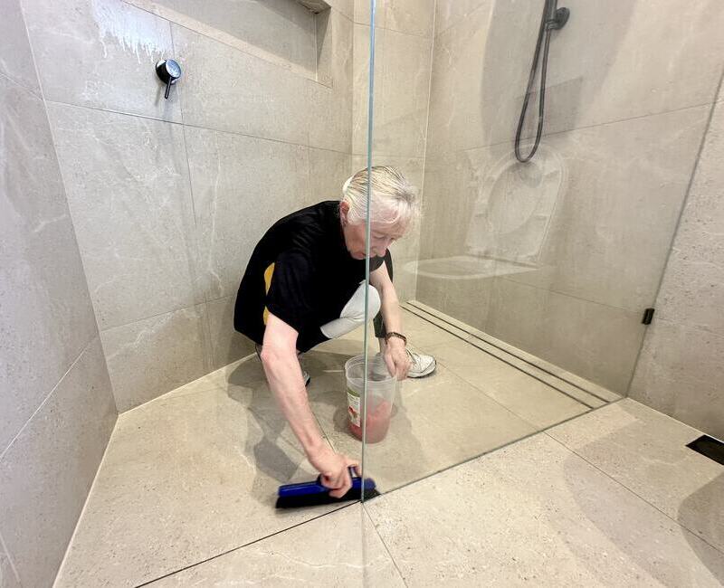 house-cleaner-brushing-shower-floor professional cleaner Lisa B cleaning shower floor with brush