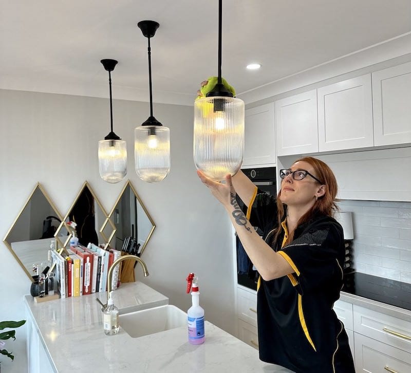 Maid2Match cleaner paying close attention to detail, cleaning light fixtures in a customer's kitchen