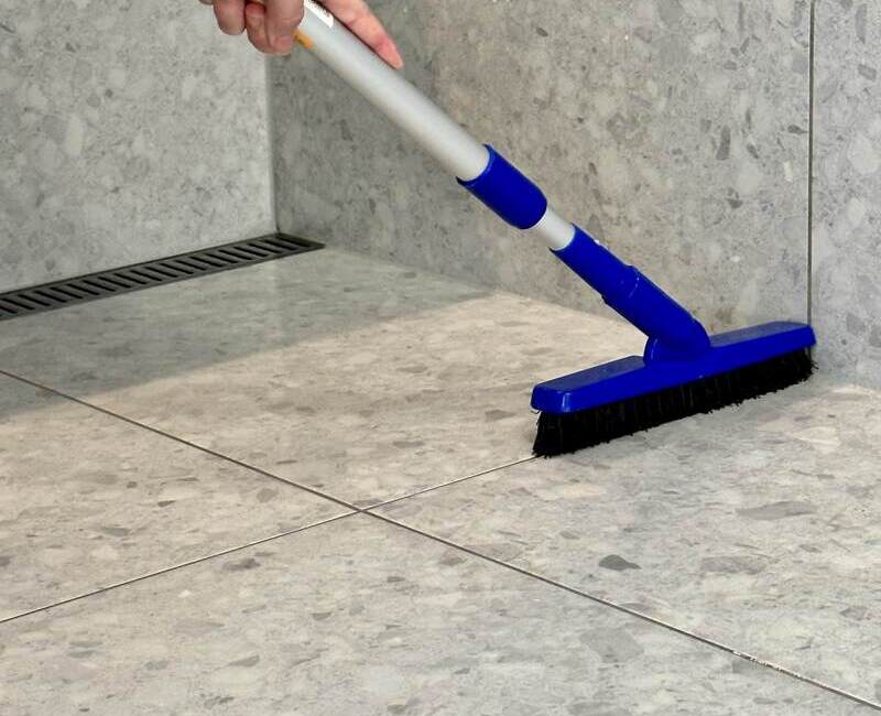 professional-cleaner-cleaning-shower-floor-grout Maid2Match house cleaner using cleaning shower floor with long handle brush