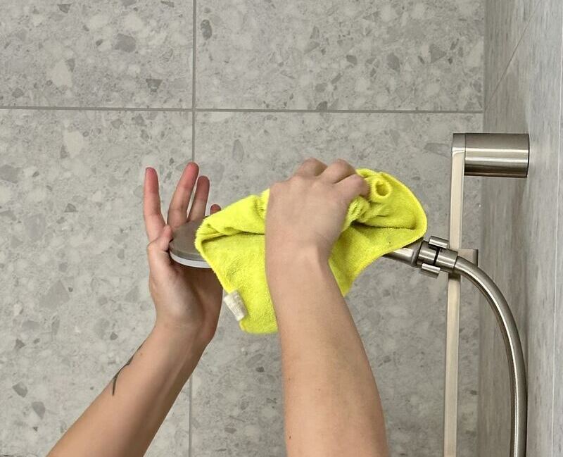 professional cleaner's hand wiping the shower head