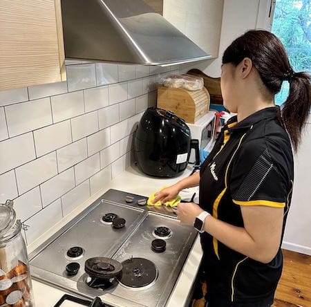 Professional Maid2Match cleaner in a customer's kitchen cleaning the stovetop