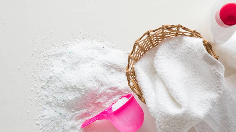 White towel in the laundry basket. Washing powder on the white background.