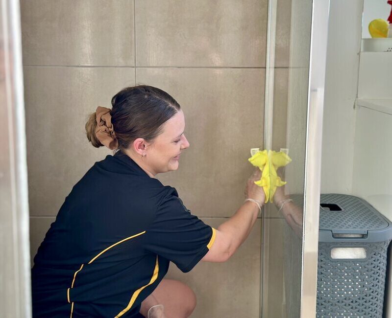 Brisbane-house-cleaner-using-microfibre-cloth-on-shower-glass Professional cleaner using microfibre cloth for shower glass cleaning