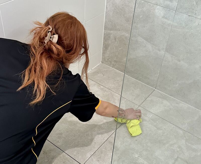 Maid2Match professional cleaner Mariachiara cleaning the grout of the shower floor tiles