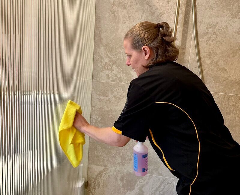 Maid2Match-Brisbane-Nicole-cleaning-shower-glass Brisbane professional house cleaner Nicole cleaning shower glass with a cleaning solution spray