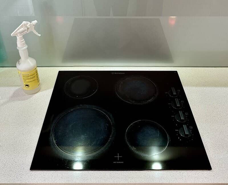 clean glass cooktop with four cooking zones and control knobs on a white benchtop