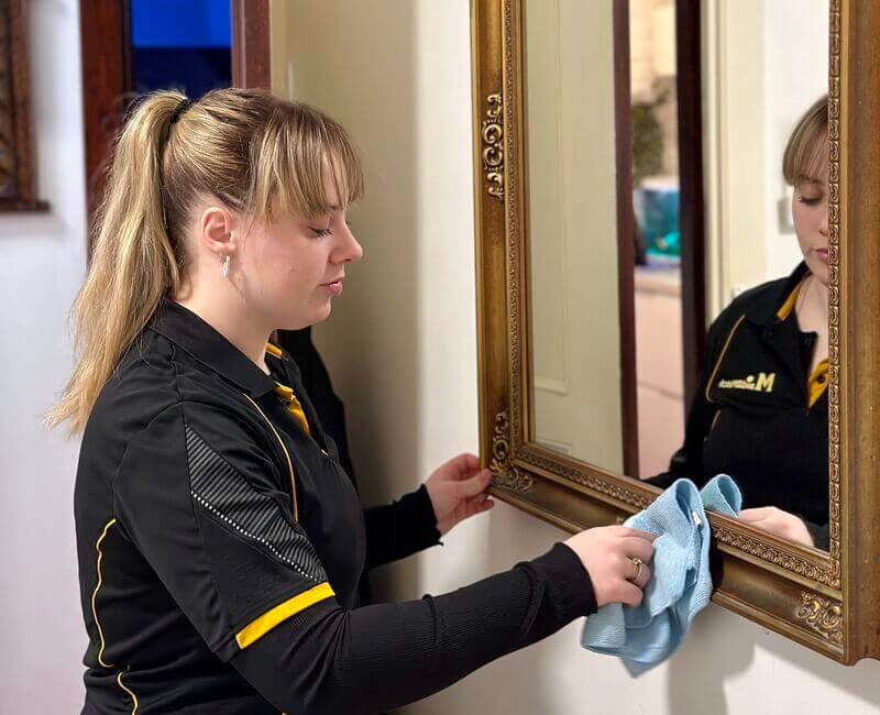 Expert cleaner Grace cleaning the mirror frame