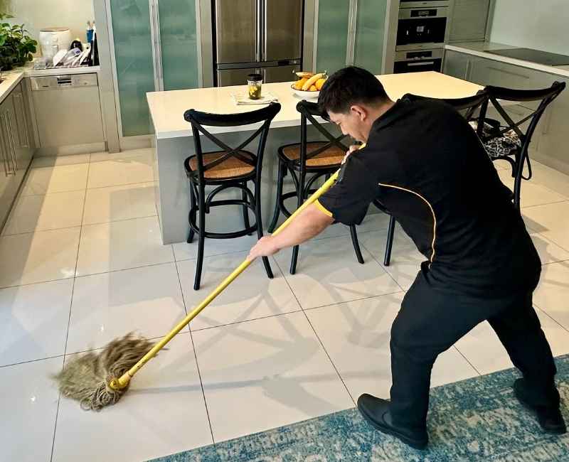 professional cleaner using string mop on tiled floor