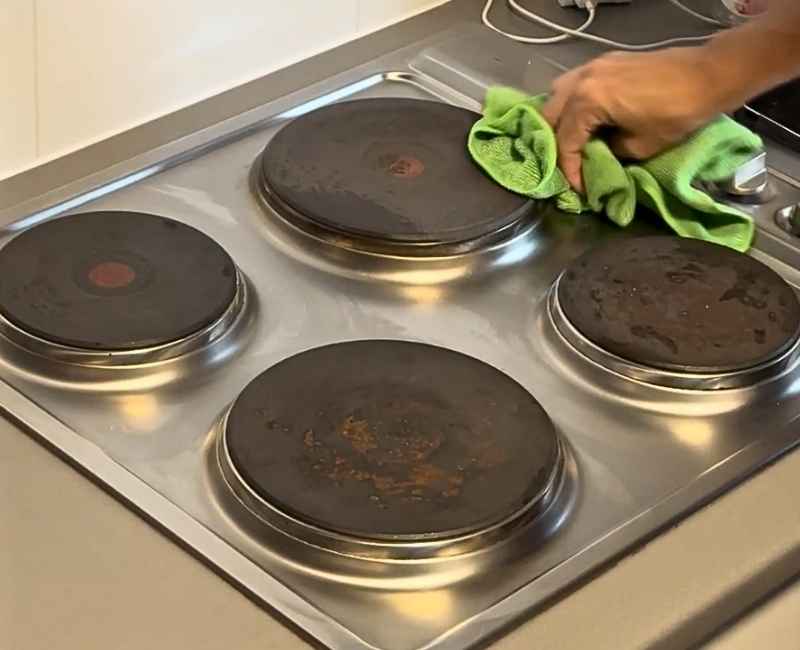 professional cleaner wiping an electric stove top surface