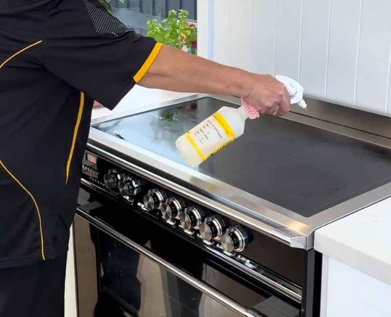 spraying cleaner on electric stove top