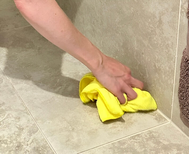Maid2Match fully trained cleaner cleaning the tile grout with a microfibre cloth