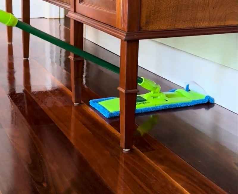 green flat mop with blue fabric used to clean wooden floor