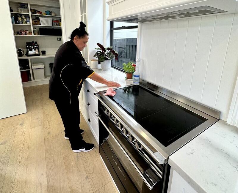 Maid2Match house cleaner Janet cleaning the induction cooktop and the surfaces around it