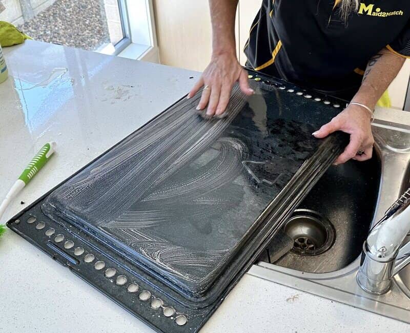 Maid2Match cleaner scrubbing an oven tray