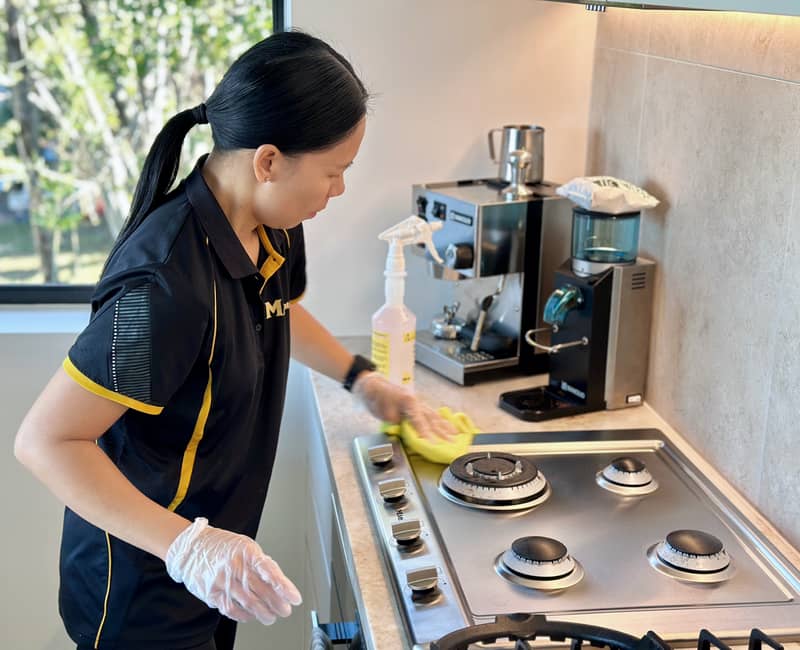 Brisbane house cleaner Paige cleaning the surface of a stainless steel stovetop