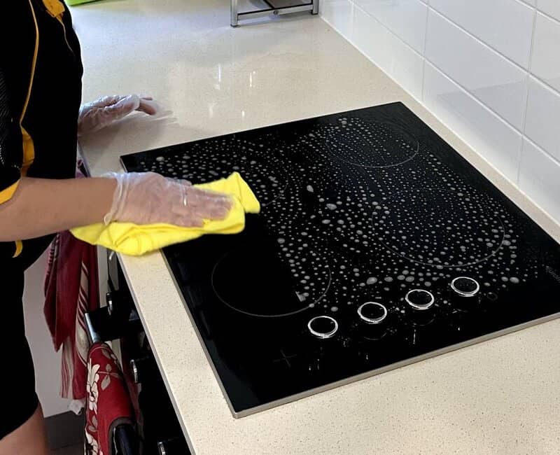 House cleaner cleaning stovetop surface