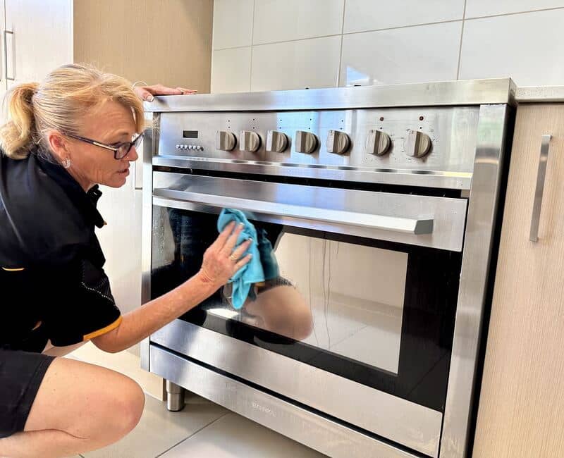 Professional cleaner Liz cleaning oven glass using microfibre cloth