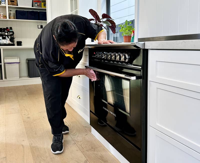 Maid2Match experienced cleaner cleaning oven glass door with microfibre cloth