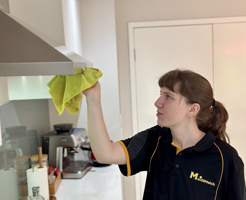 Experienced house cleaner Kayleigh wiping rangehood with microfibre cloth