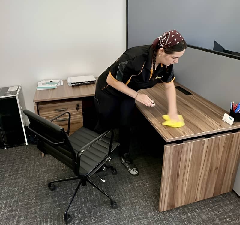 Sprining cleaning. Maid2Match Tatyanna wiping the surface of a table in the office.