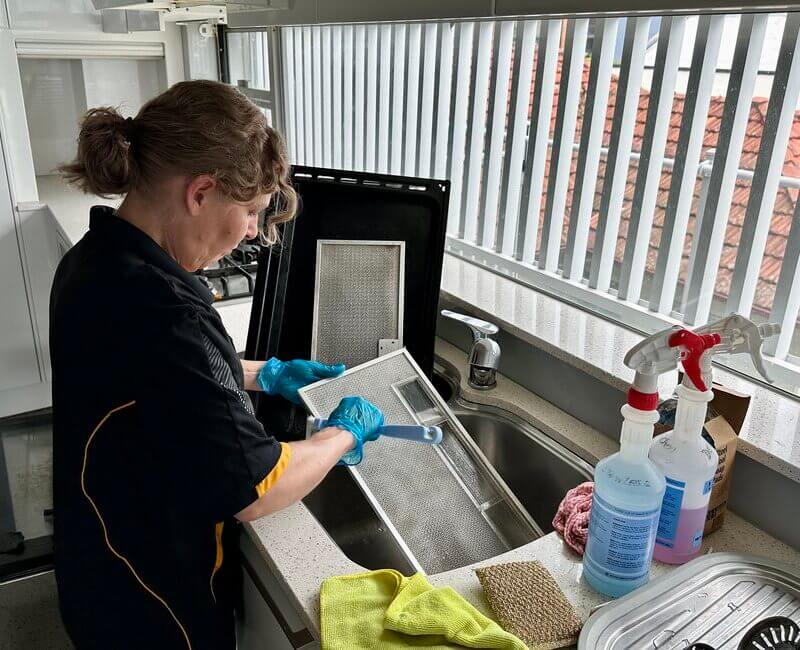 Maid2Match cleaner and Assistant Team Leader Nicole cleaning rangehood filter in a kitchen sink