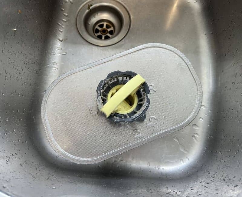 dirty dishwasher filter on a kitchen sink