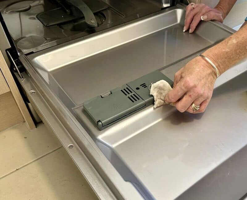 wiping the soap dispenser area of a dishwasher
