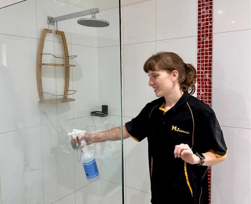 Maid2Match Brisbane house cleaner Kayleigh uses commercial cleaner to clean shower glass