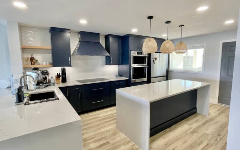 Modern kitchen with blue painted cabinets, white island, and wood accents