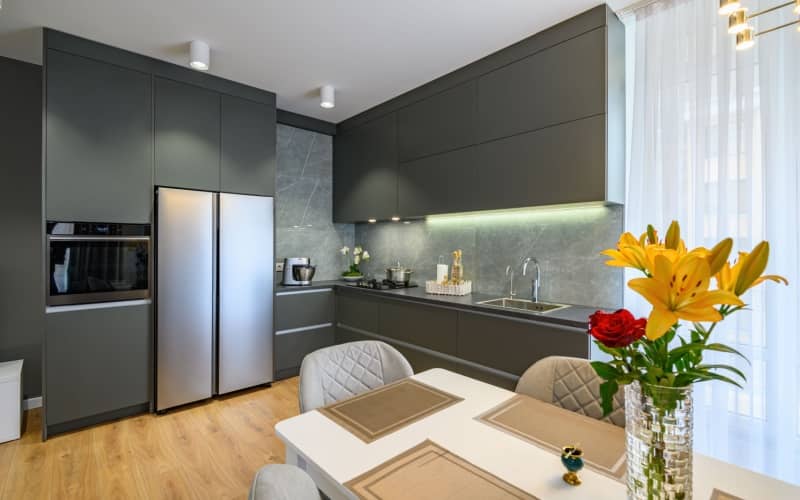 Modern luxury dark gray kitchen with matte cabinets and a dining table