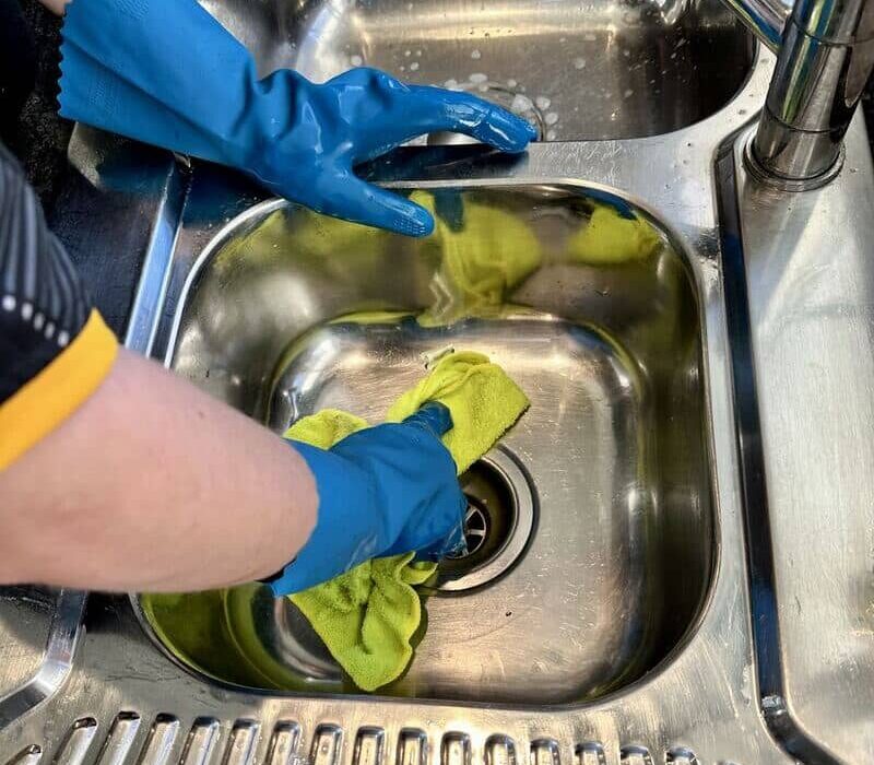 house cleaner wiping the kitchen sink and drain