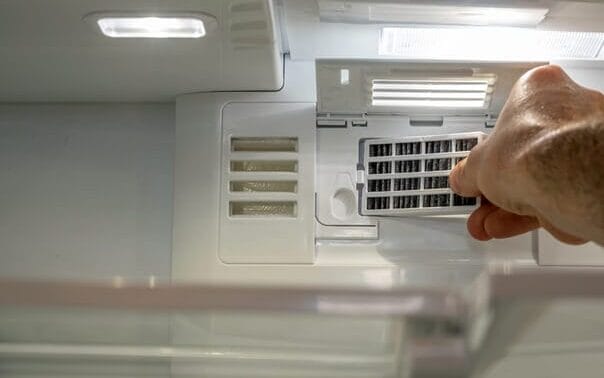man's hand on a refrigerator air filter