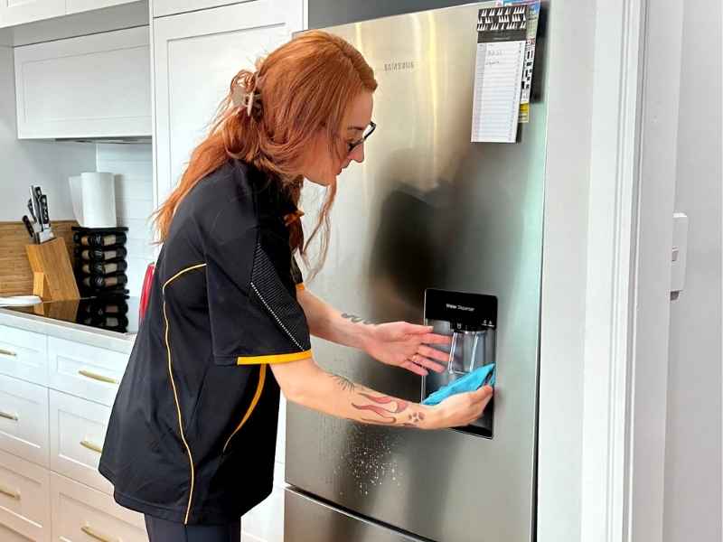 professional cleaner cleaning fridge water dispenser nozzle