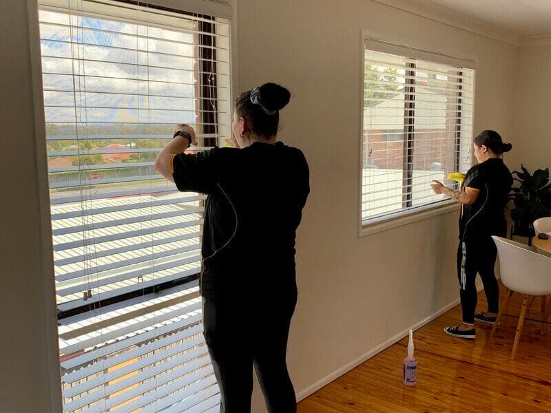 two professional cleaners cleaning Venetian blinds