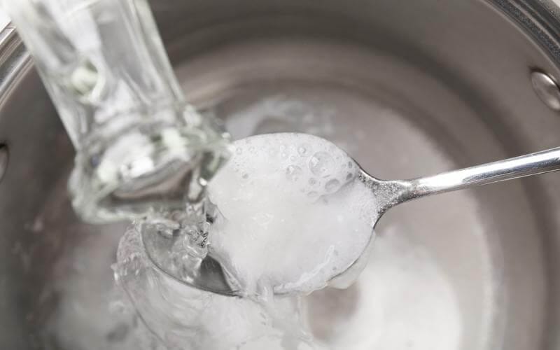 pouring vinegar on spoonful of baking soda