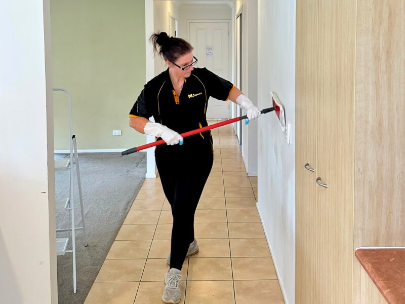Brisbane professional cleaner Renee cleaning the wall with a flat mop