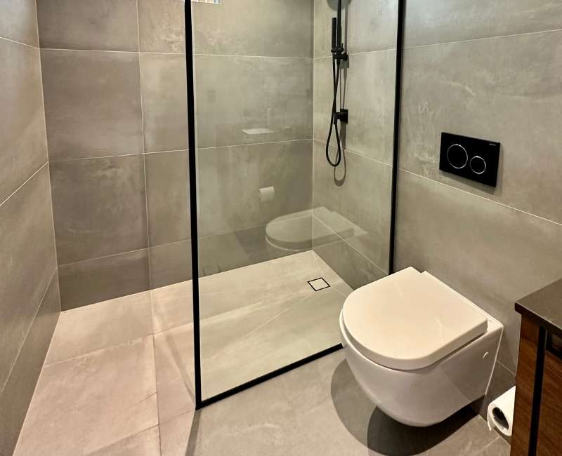Clean bathroom surface with tiled floor, glass shower wall, and porcelain toilet
