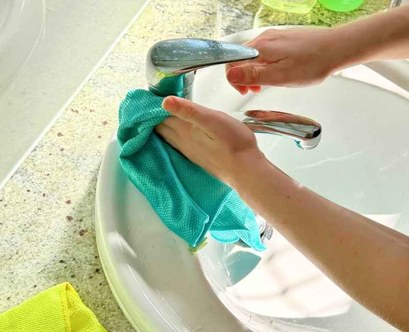 professional cleaner cleaning bathroom sink with cloth and soap