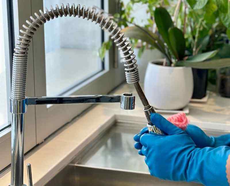 house cleaner cleaning kitchen sink faucet