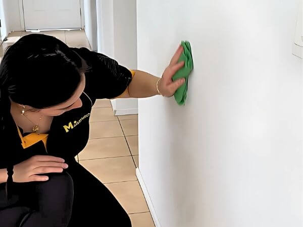professional cleaner wiping wall with green microfibre cloth