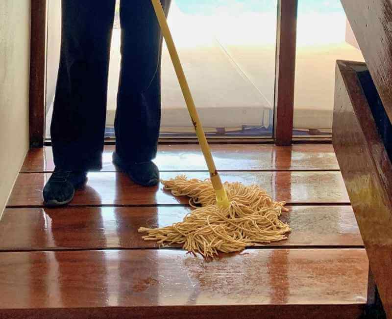 house cleaner mopping wooden floor using string mop