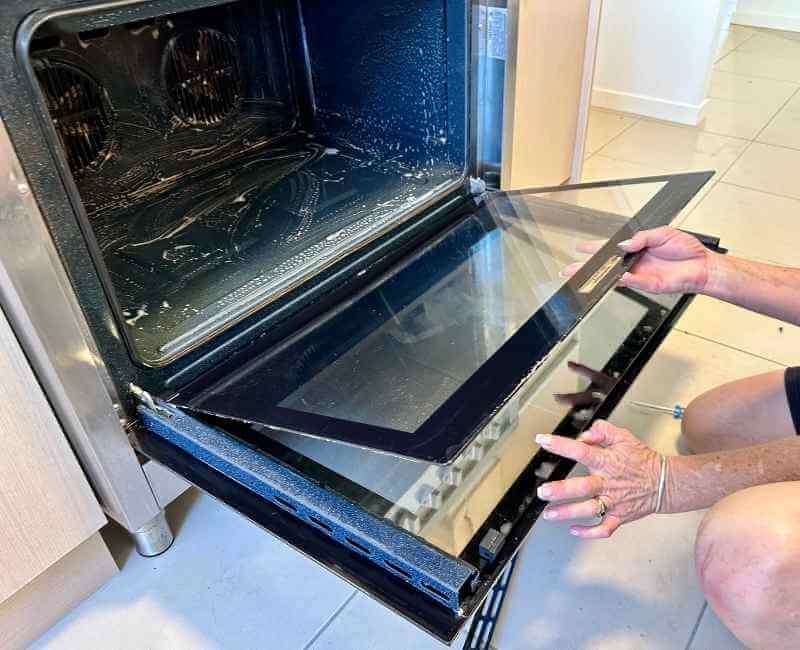 professional house cleaner cleaning the inside of an oven