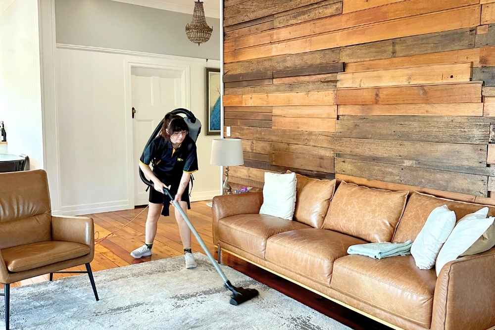 professional cleaner using vacuum to clean living room