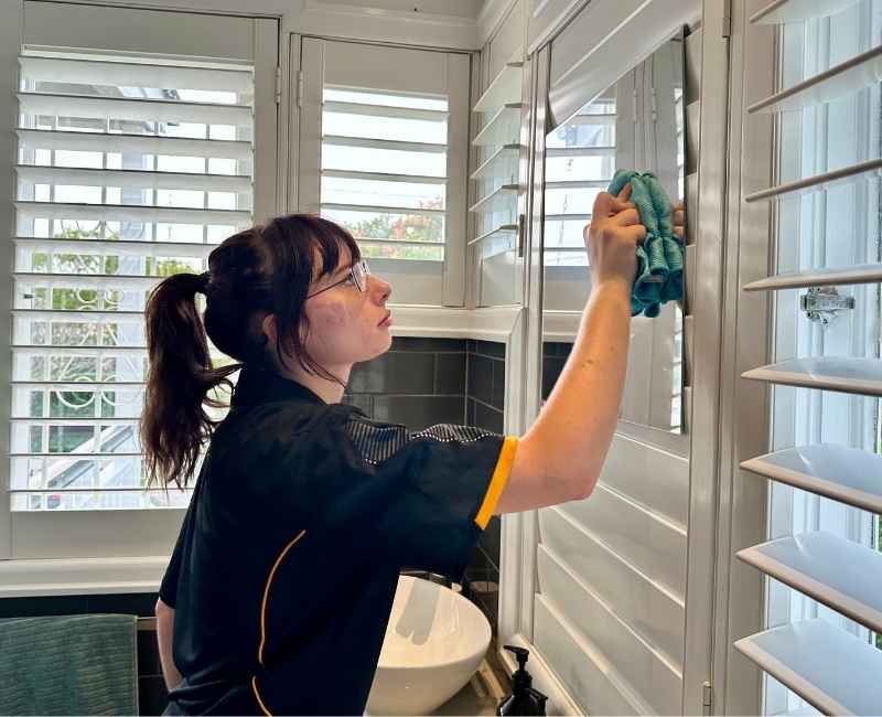 Professional House cleaner River cleaning a bathroom mirror