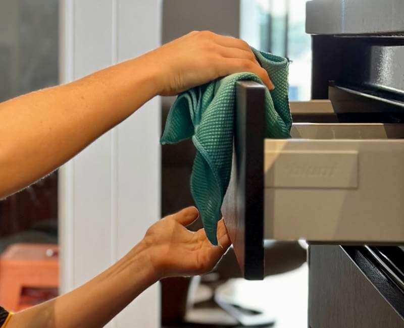 professional cleaner wiping cabinet using microfibre cloth