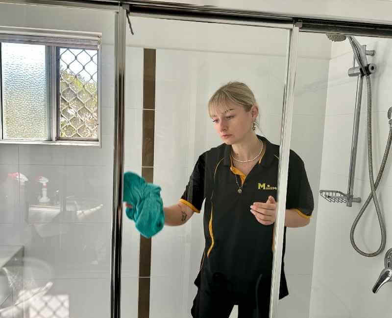 Maid2Match Brisbane Professional Cleaner, Casey using microfibre cloth to clean shower glass surface