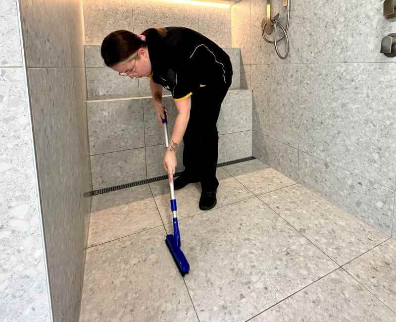 Maid2Match Gold Coast Professional Cleaner, Kirsten using brush to clean shower floor